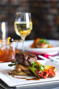 einen weißen Teller mit Steak und Gemüse und ein Glas Wein in der Unterkunft The Centennial Hotel in Concord
