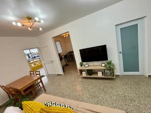聖胡安的住宿－Urban Tropical Oasis in San Juan，客厅配有平面电视和桌子。