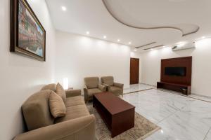 uma sala de estar com um sofá e uma televisão de ecrã plano em Masharef Abha Suites em Abha