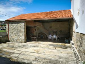 a stone building with a patio with chairs in it at Casa tradicional en el Camino dos Faros Costa da Morte in Ponteceso