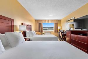 a hotel room with two beds and a flat screen tv at Coast Fraser Inn in Williams Lake