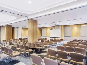 une salle de conférence avec des chaises et un écran dans l'établissement ibis Jakarta Raden Saleh, à Jakarta