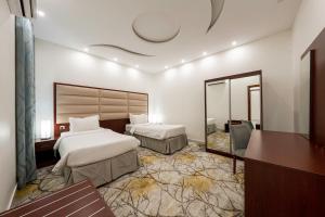 a hotel room with two beds and a mirror at Masharef Abha Suites in Abha