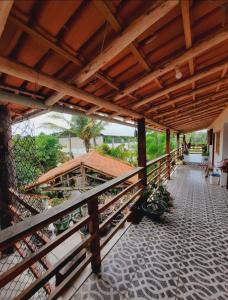 an outdoor patio with a wooden roof and a balcony at ITAÚNAS Pousada NOSSA PALHOÇA 1 in Itaúnas