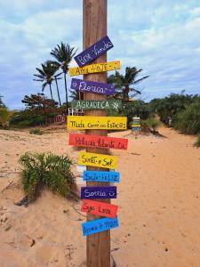 a wooden pole with signs on the beach at ITAÚNAS Pousada NOSSA PALHOÇA 1 in Itaúnas +14 photos