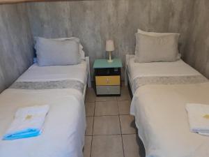 two twin beds in a room with a night stand at Ríos que nos unen in Colonia del Sacramento