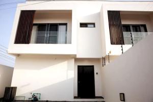 una casa blanca con una puerta negra en Modern Townhouse near Beach en Accra