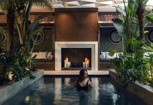 a woman in a swimming pool with a fireplace at Boutique Hotel Esplanade in Paestum