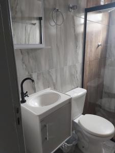 biała łazienka z toaletą i umywalką w obiekcie Residência Aguiar w mieście Guaratuba