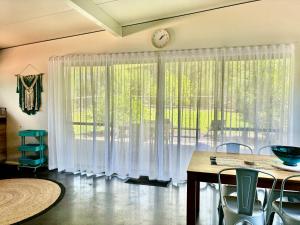 a dining room with a table and a clock on the wall at Panda's Patch Dunsborough in Dunsborough