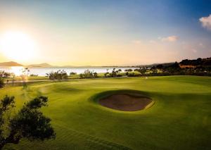 a view of a golf course with the ocean in the background at Mandarin Oriental, Costa Navarino in Pylos