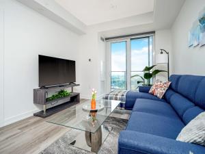 un salon avec un canapé bleu et une télévision dans l'établissement Modern 1BR Condo - King bed - Cityscape Views, à Kitchener