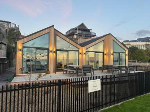 Una casa con ventanas de cristal y una mesa y bancos. en Absolute Lakefront House, en Taupo