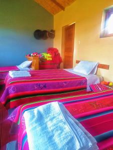 a room with three beds with colorful blankets on them at TITICACA'S SALA UTA in Puno