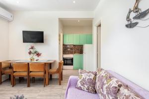un soggiorno con tavolo e una cucina con armadi verdi di Kassiani-Sofia Cottage a Gouviá