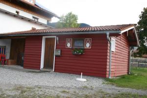 ein rotes Haus mit einem Fenster und einem Blumenkasten in der Unterkunft Blockhütte in Trauchgau