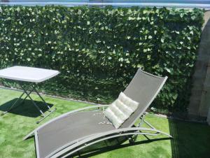 een stoel en een tafel voor een groene heg bij Lugar tranquilo in Colonia del Sacramento