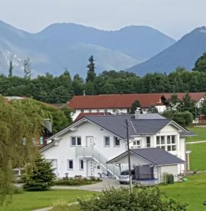 Une grande maison blanche avec des montagnes en arrière-plan dans l'établissement Ferienwohnung Hoherting, à Prien am Chiemsee