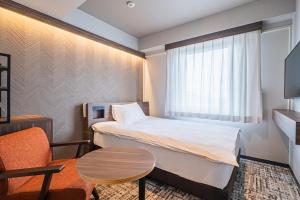 a small hotel room with a bed and a table at Nagoya Kasadera Hotel in Nagoya