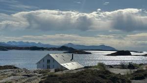 a white house on the shore of a body of water at Sveggvika Atlantic Home in Averoy