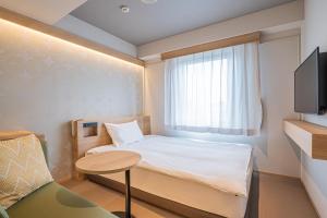 een kleine kamer met een bed en een raam bij Nagoya Kasadera Hotel in Nagoya
