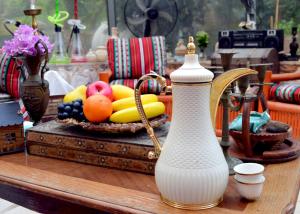 a table with a white vase and a basket of fruit at بيت الطبيعة nature house in Jerash