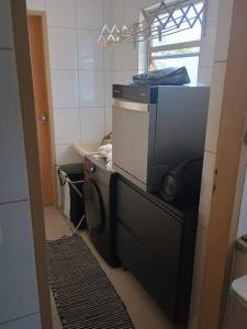 a kitchen with a washing machine and a microwave at Quarto Cambuí l Apto compartilhado in Campinas