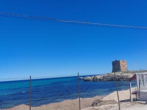 vista sulla spiaggia con molo sullo sfondo di Borgo La Chiusa a Cinisi