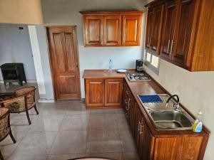 eine Küche mit Holzschränken und einem Waschbecken in der Unterkunft Résidence Élisabeth in Fondjomékwet