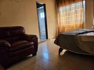 FondjomékwetにあるRésidence Élisabethのベッドルーム(ソファ、ベッド、椅子付)