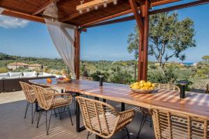 Un comedor al aire libre con una mesa y sillas de madera. en Lakka Hill House, en Zakynthos