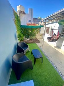 eine Terrasse mit 2 Stühlen, einem Tisch und Gras in der Unterkunft Exclusiva casa céntrica in Chascomús