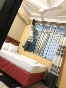 een slaapkamer met een bed en een raam met gordijnen bij Cam Lodge in Tanga