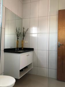 a white bathroom with a toilet and a sink at Casa Agradável com muito espaço 