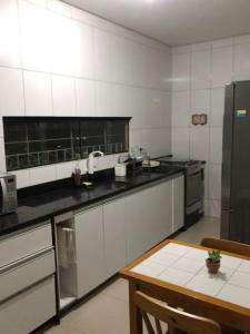 a kitchen with white walls and a black counter top at Casa Agradável com muito espaço 