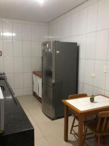 a kitchen with a stainless steel refrigerator and a table at Casa Agradável com muito espaço 