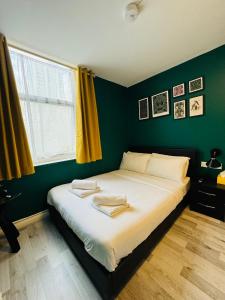 a bedroom with a large bed with green walls at Unique Studio Flat in City 1110 in London