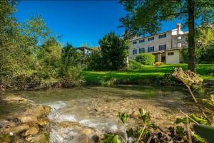 a house with a river in front of a building at Holiday house with a swimming pool Buzet, Central Istria - Sredisnja Istra - 22842 in Buzet