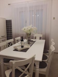 una mesa de comedor blanca con una botella de vino y flores en Seaside family friendly house with a swimming pool Orebic, Peljesac - 23009, en Orebić
