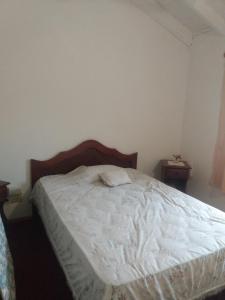 1 dormitorio con 1 cama con sábanas blancas y 2 mesas en Residencia Mabel en Posadas