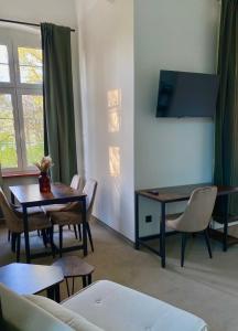 - un salon avec une table, des chaises et une télévision dans l'établissement Zamek Nowęcin, à Łeba