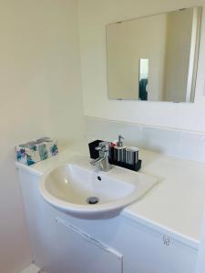 een witte wastafel in een badkamer met een spiegel bij R & N holiday home in Manchester