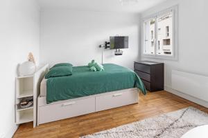 - une chambre blanche avec un lit et une couverture verte dans l'établissement Studio Reze, à Rezé