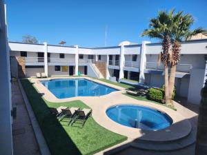 a view of a building with a pool and palm trees at Hotel Paraiso in Puerto Peñasco