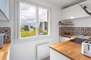 a kitchen with white counters and a window at Studio Cosy - Au pied du tram - Parking - WIFI in Rezé