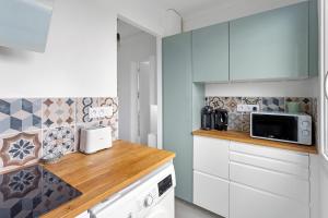 une cuisine avec des placards blancs et un comptoir en bois dans l'établissement Studio Reze, à Rezé