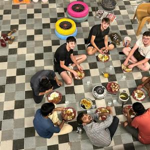 un gruppo di persone seduti sul pavimento che mangiano cibo di Mohit Paying Guest house a Varanasi