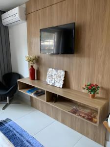 a living room with a television on a wooden wall at Flat Manacas Granja Brasil Itaipava in Itaipava