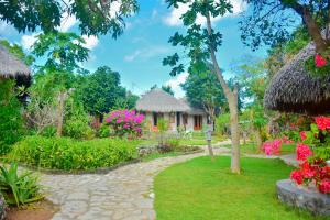 a garden with flowers and a building at Mulia Bungalows in Nembrala