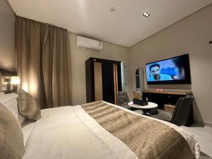 a hotel room with a bed and a flat screen tv at شقق المجرات الذهبية المخدومة in Al Baha